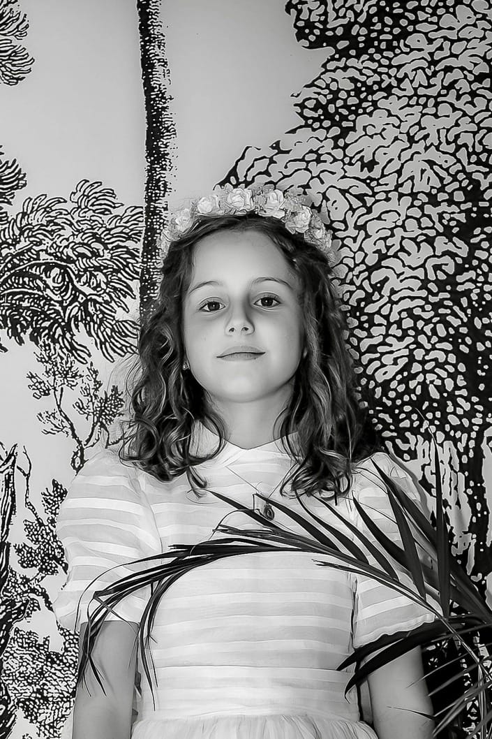 Niña de comunión entre hojas de palma, en blanco y negro