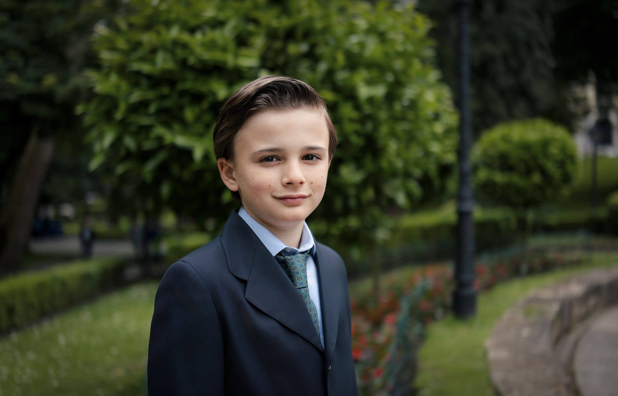 Niño con traje azul marino en un jardín