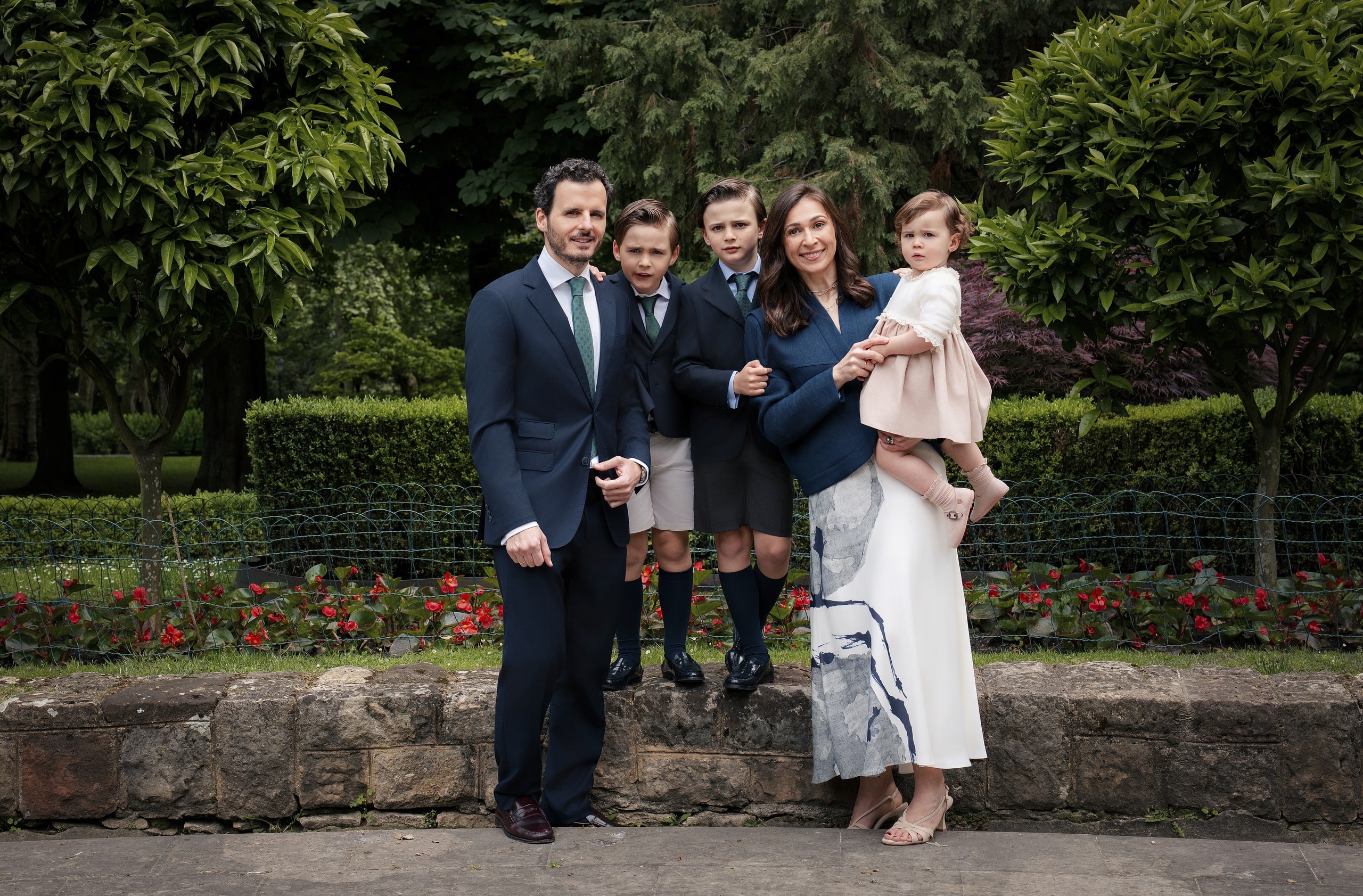 Familia de seis en un jardín, junto a un muro de piedra